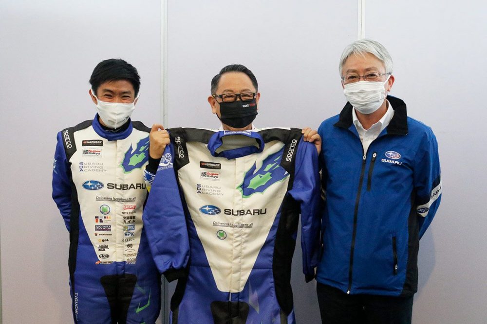 スバルの中村社長からレーシングスーツを受け取ったモリゾウ選手（写真は左から井口選手、モリゾウ選手、中村社長）