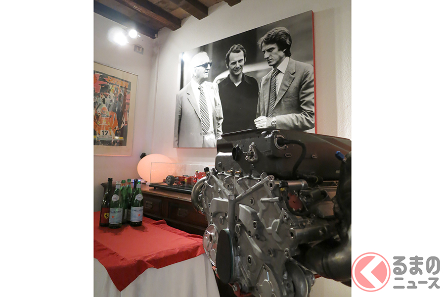 フェラーリの本物のエンジン、そしてモンテゼーモロとラウダと一緒に撮影されたエンツォの写真パネル