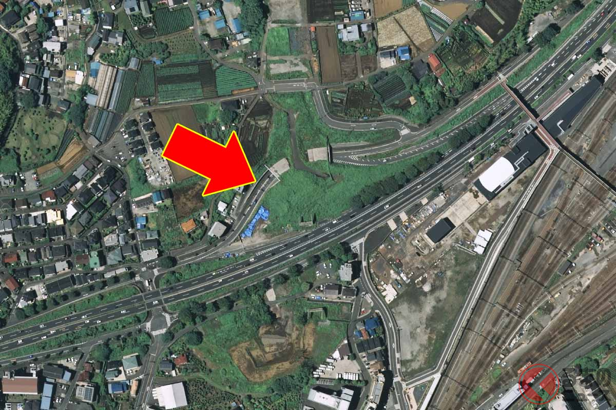 立体交差ランプの用地を避けてカーブを描く環状2号線の側道(国土地理院の空中写真に編集部が矢印を追加)