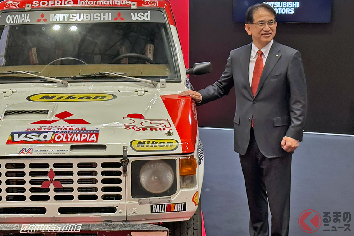 画像は三菱自動車工業 岸浦恵介 代表執行役社長兼 COOと、1985年「ダカールラリー」総合優勝を果たした三菱の初代「パジェロ」参戦車両［「オートモビルカウンシル2026」三菱ブースにて（幕張メッセ）］