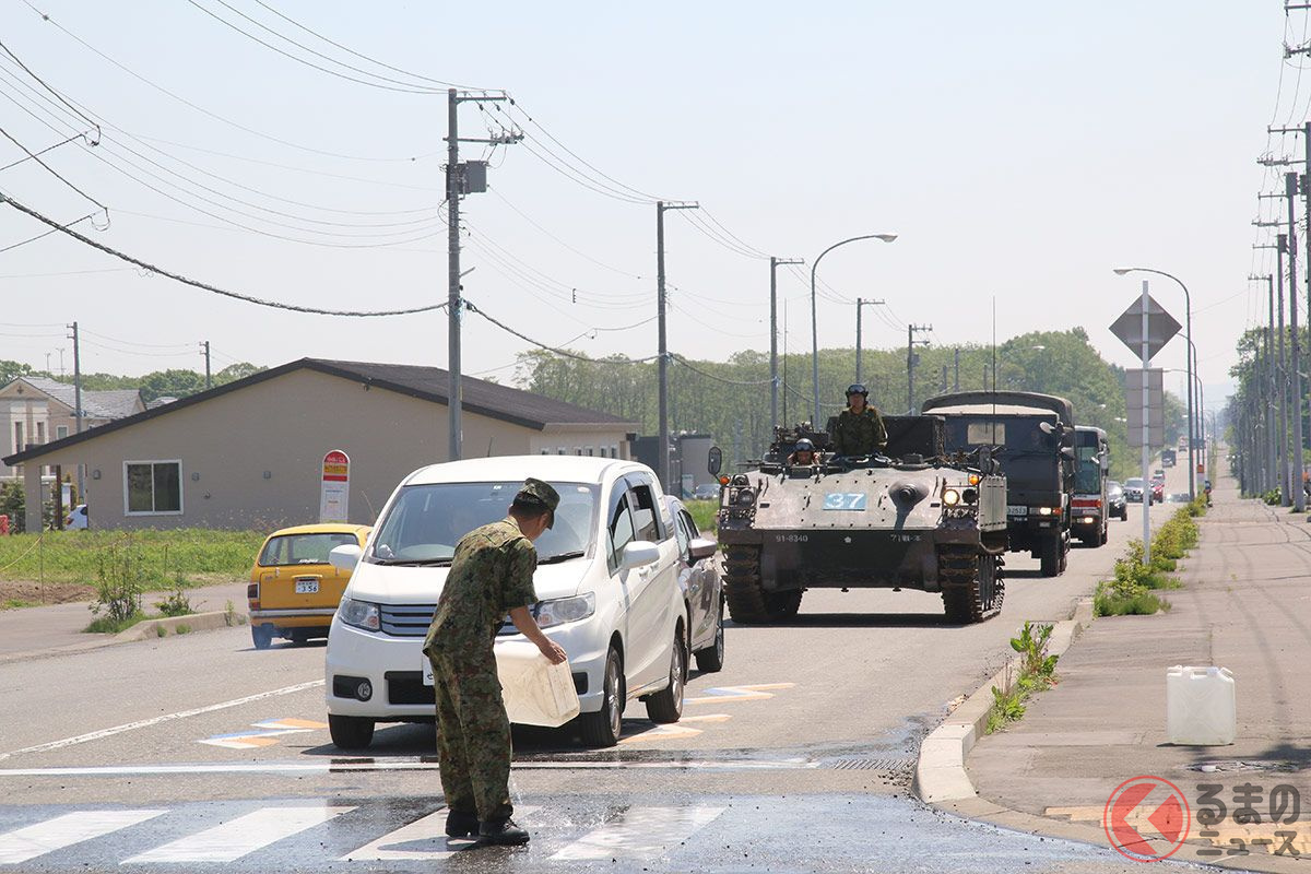 一般車に混じって信号待ちする73式装甲車。塗面を保護する散水作業が続く。(画像:月刊PANZER編集部撮影)
