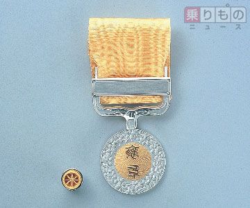 褒章のデザインは、「褒章」の2字を桜の花で飾った円形のメダルで、綬（リボン部分）の色（紅、緑、黄、紫、藍、紺）により区分される（画像：内閣府）。